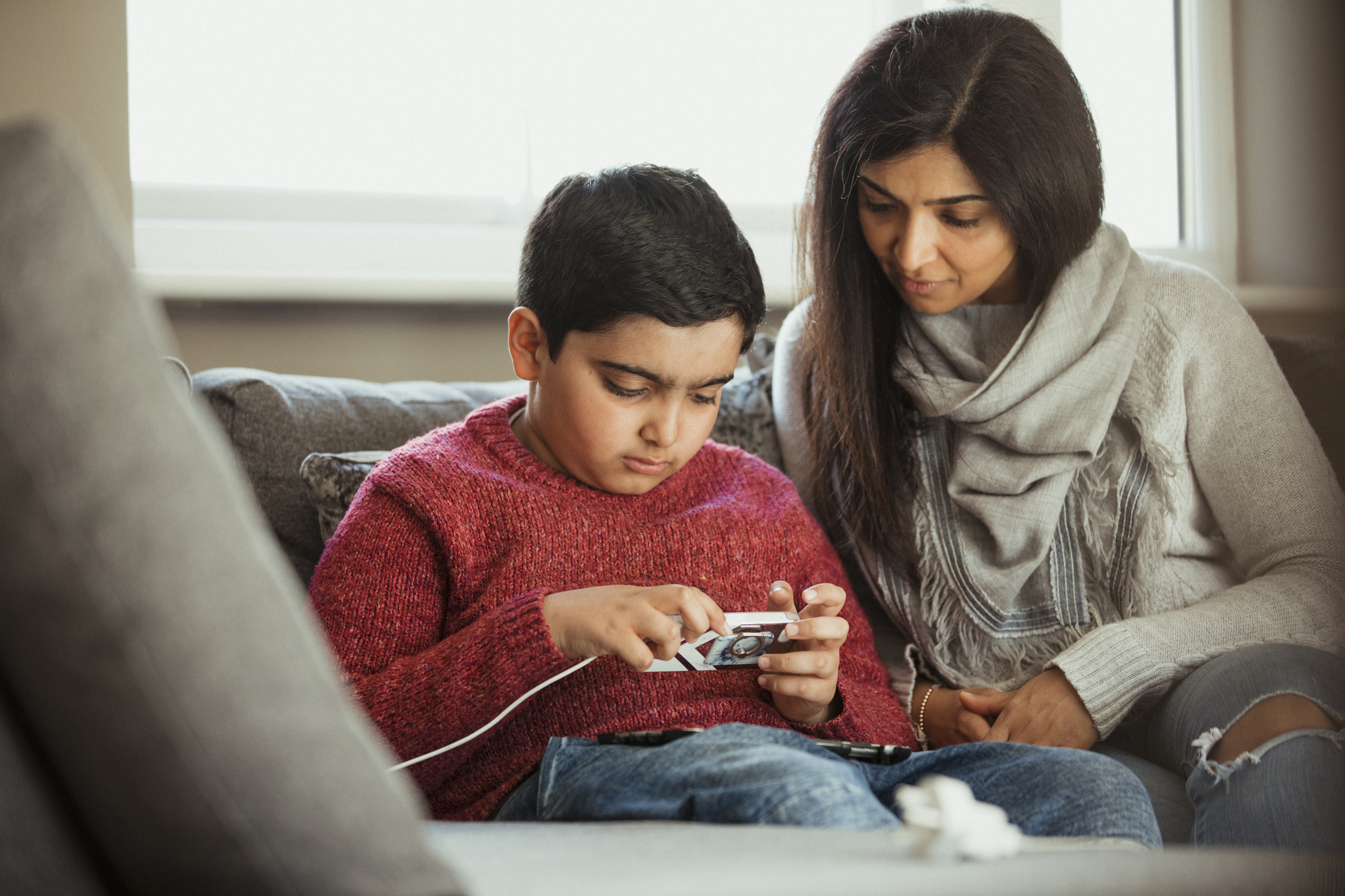Mother sitting down on a sofa with her son